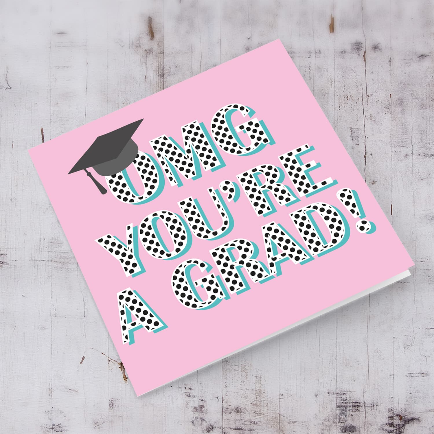 Pink background graduation card with polka dot wording and graduation hat in English