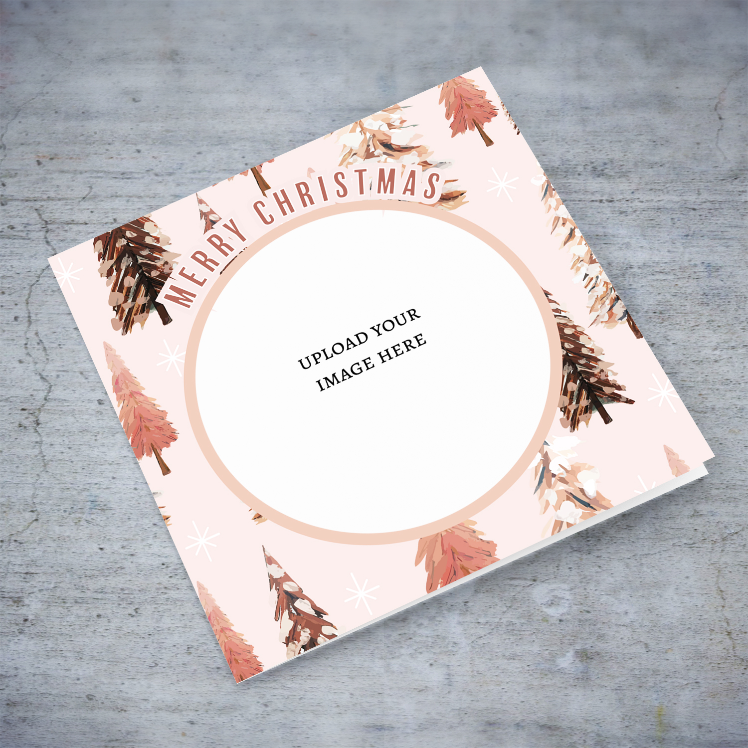 An open Christmas card in various pink tones, featuring a background with different Christmas trees in English