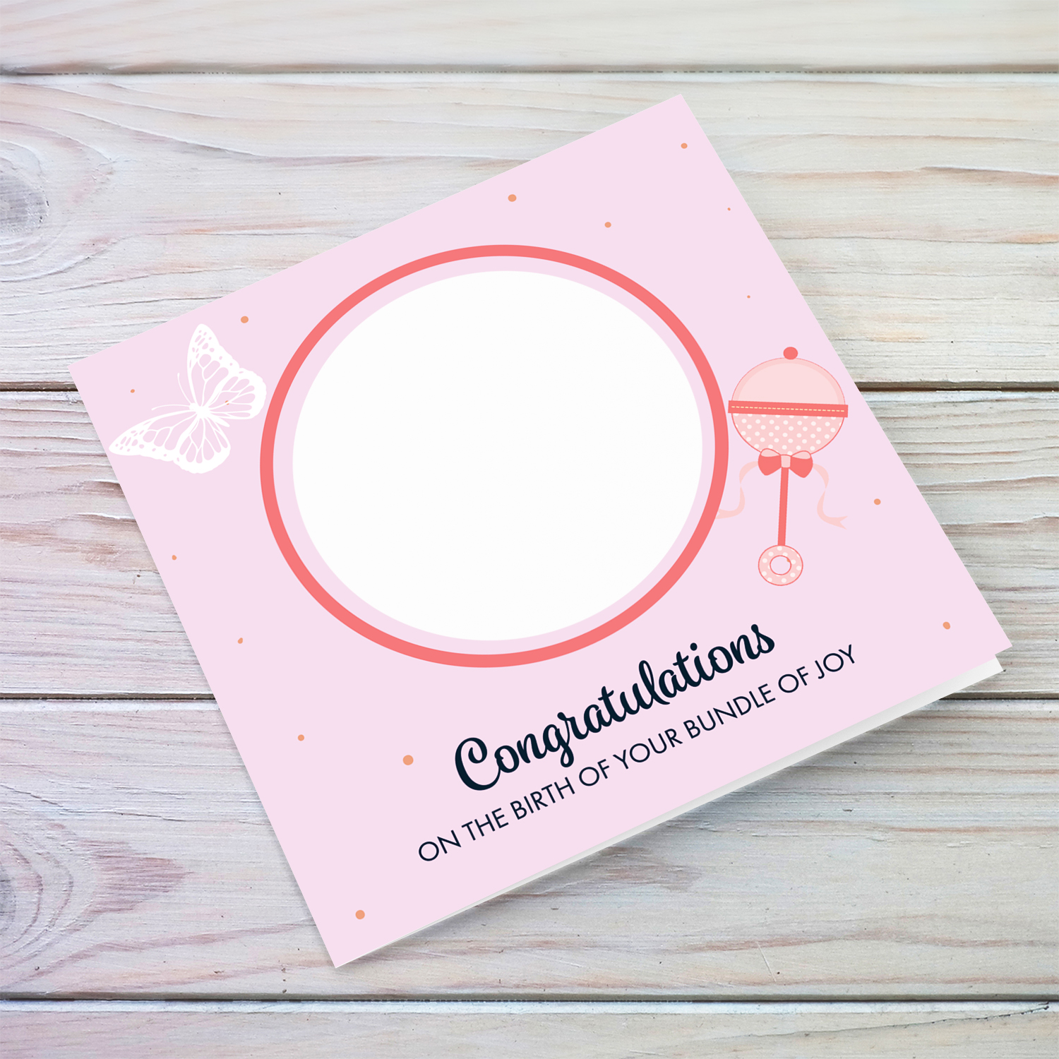 Photo new born card with pink spotted background, with butterfly and pink rattle in English