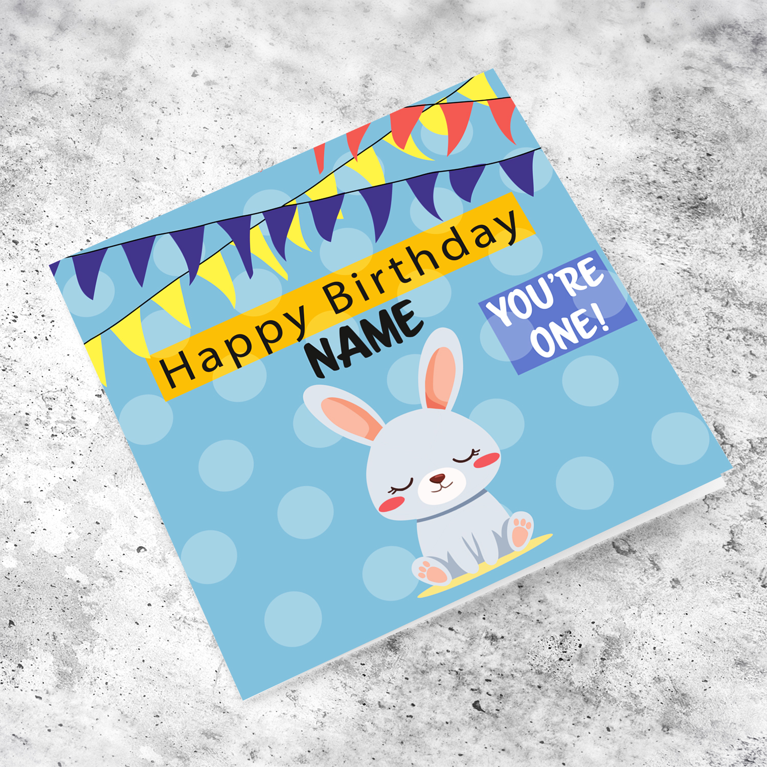 A cute bunny themed first birthday card in blue spotted background with colourful bunting in English