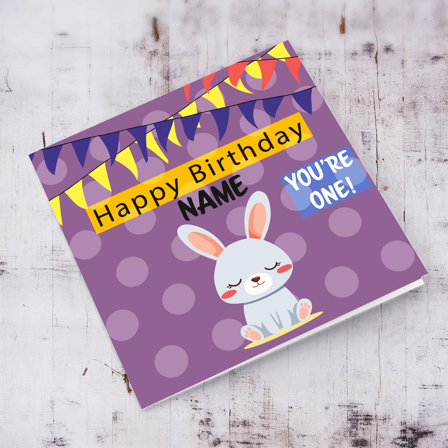 A cute bunny themed first birthday card in purple spotted background with colourful bunting in English