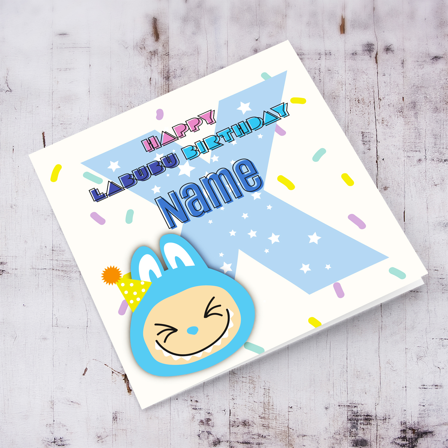 A colourful birthday card featuring a blue labubu wearing a party hat, with colourful confetti, and personalisable with name & age (Personalisable & Enter Age)
