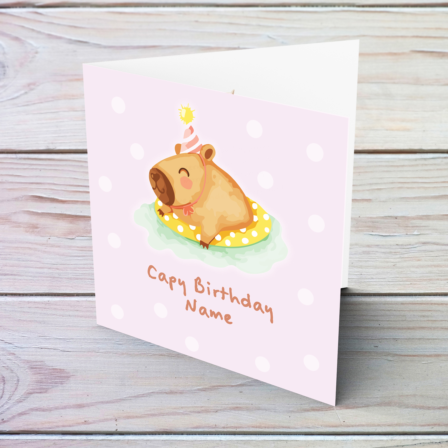 A cute birthday card featuring a capybara swimming and wearing a party hat, in a pink spotted background in English (Personalisable)