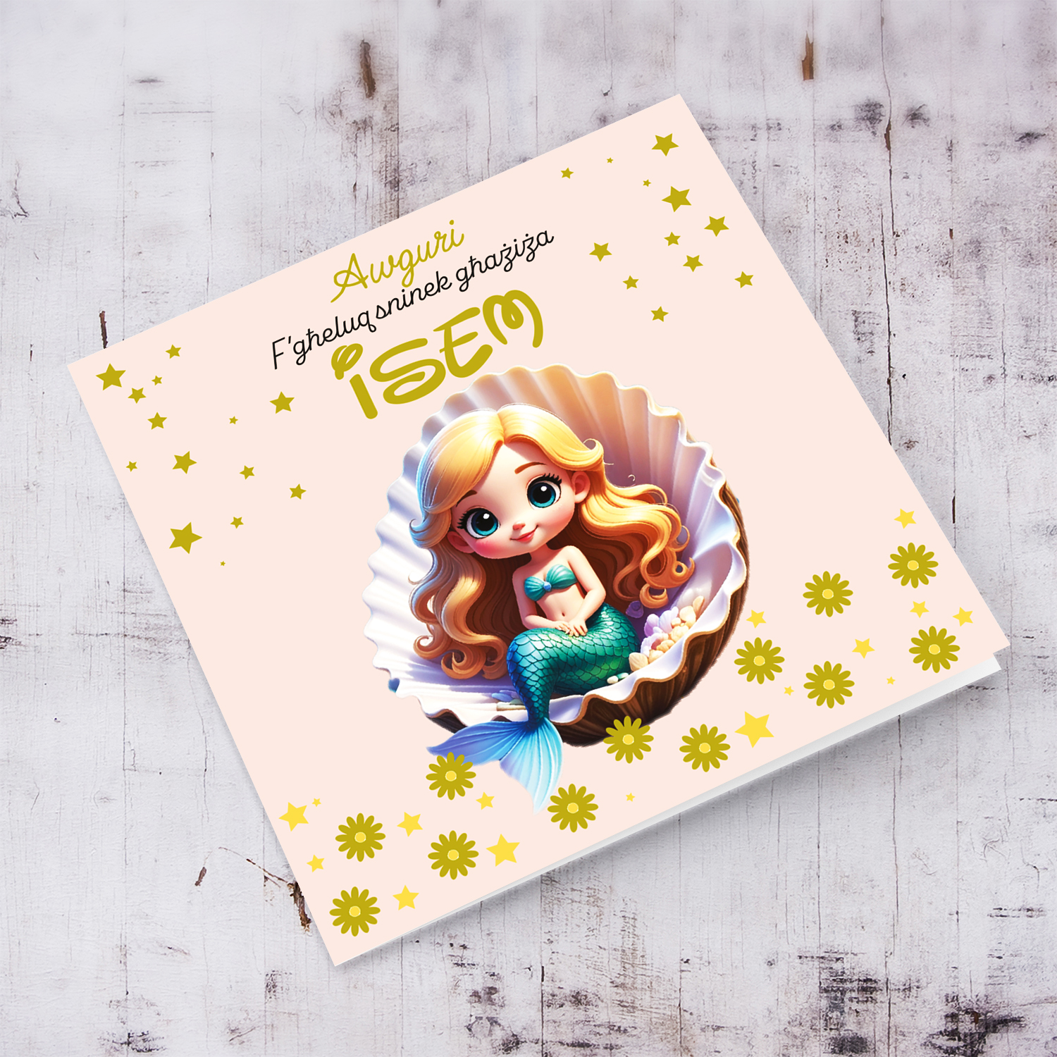 A cute birthday card in light pink background with a blonde haired mermaid, sitting in an oyster shell, with golden stars and flowers in Maltese
