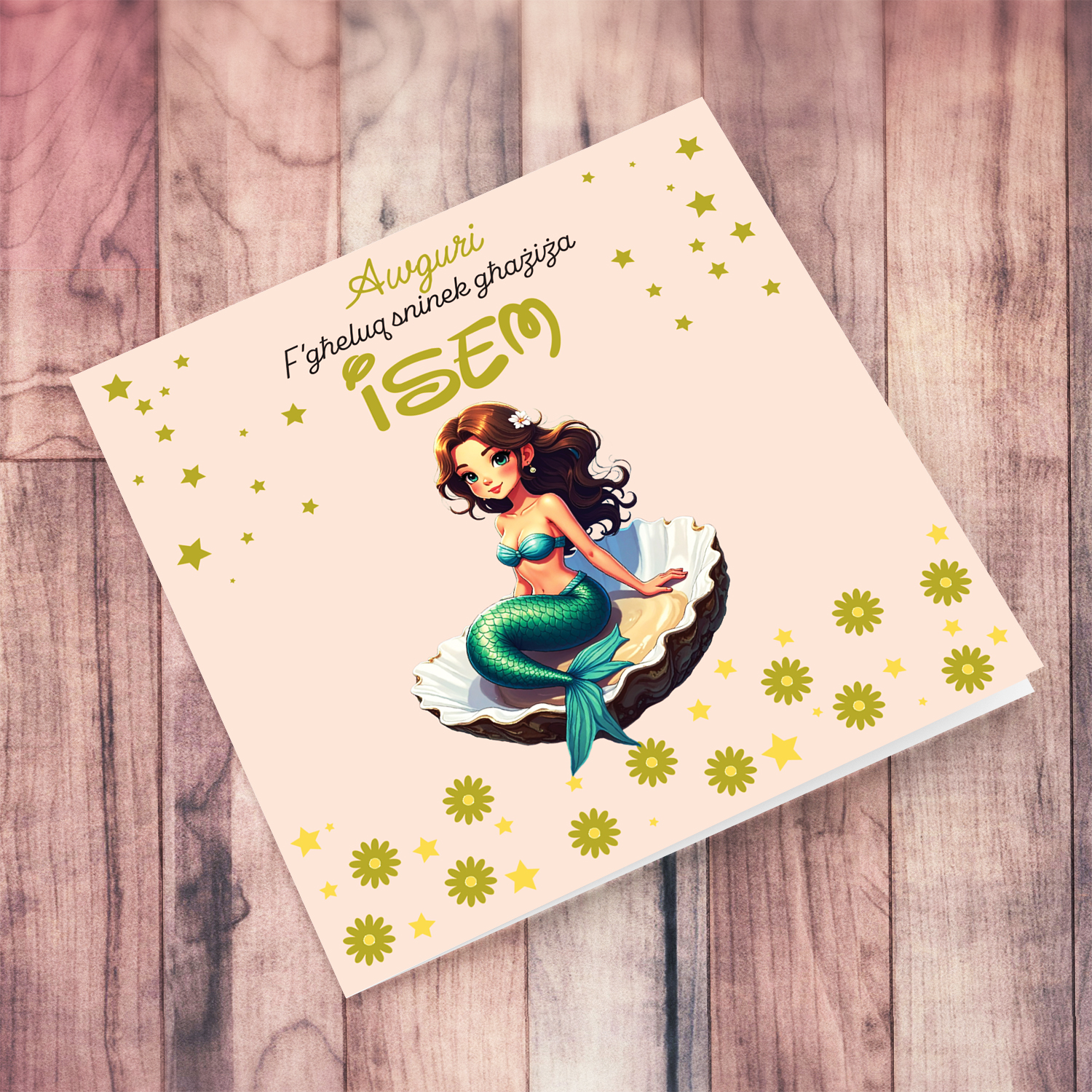A cute birthday card in light pink background with a brunette mermaid, sitting in an oyster shell, with golden stars and flowers in Maltese