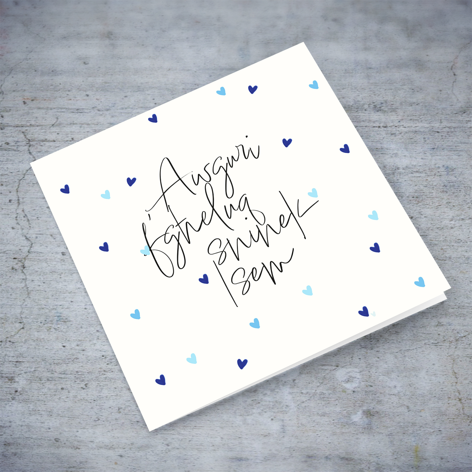 A birthday card in a neutral cream colour background with scattered blue hearts in Maltese