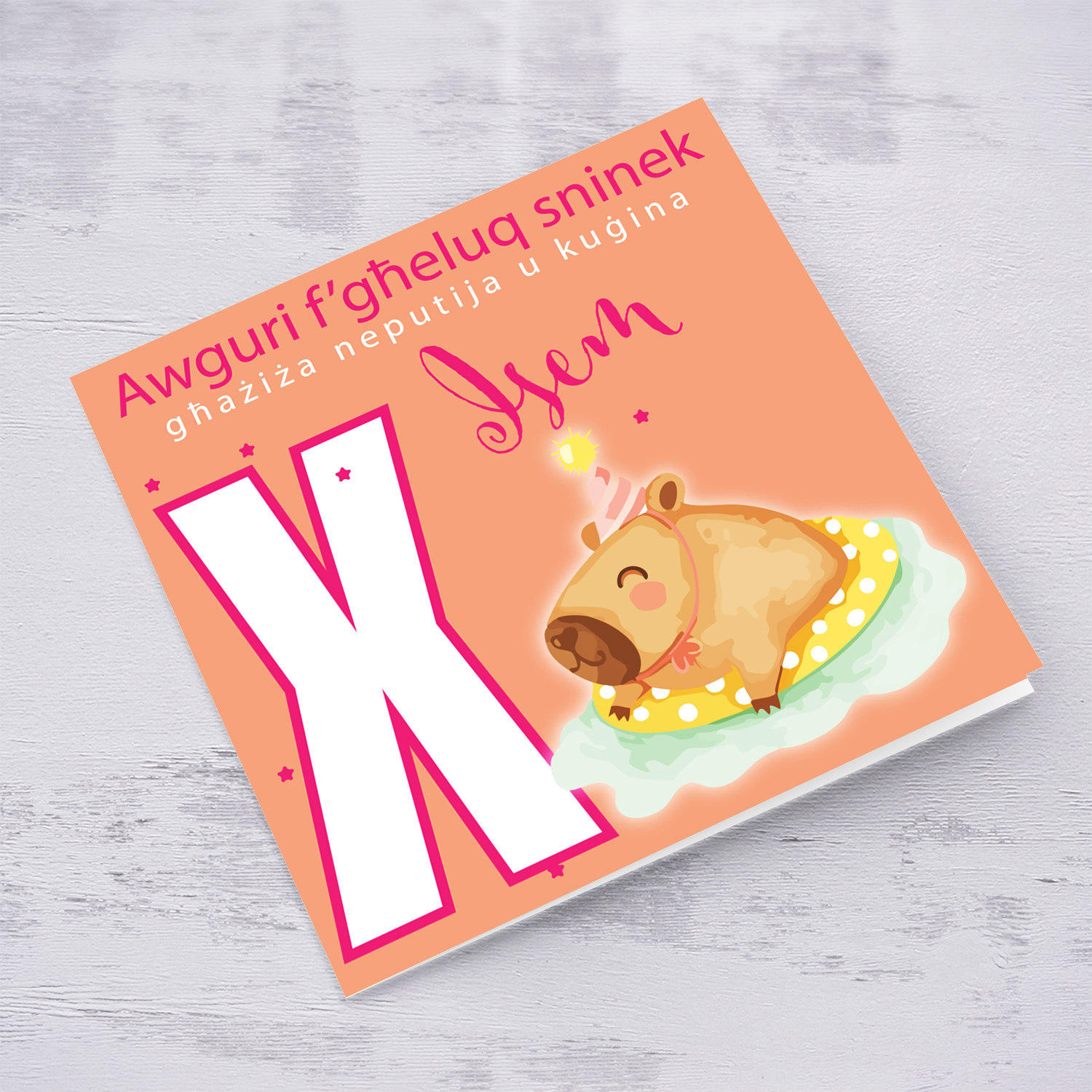 A cute birthday card for niece & cousin featuring a capybara swimming and wearing a party hat, personalisable with name and age in pink tones in Maltese (Personalisable + Enter Age)