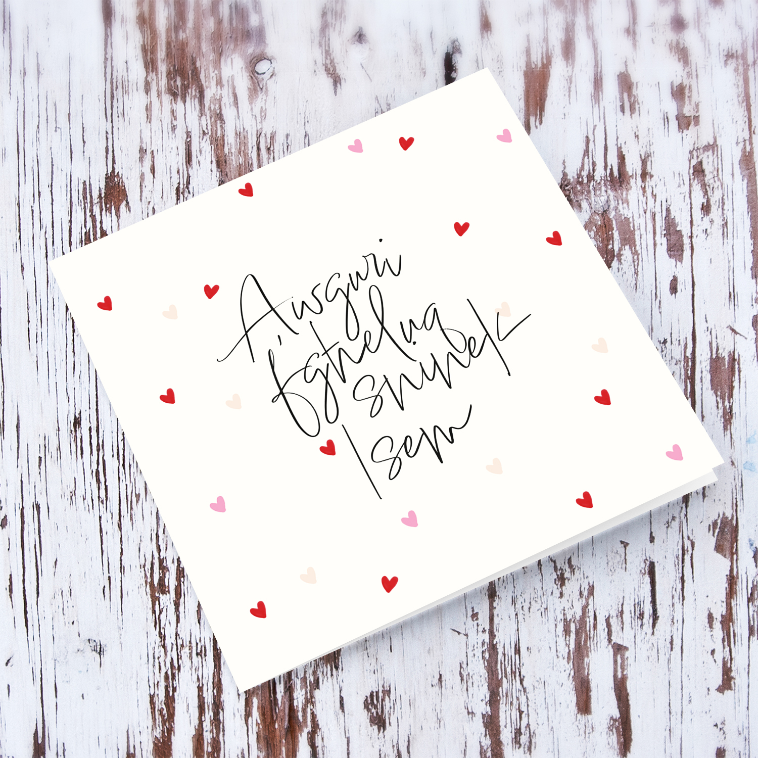 A cream coloured birthday card with scattered red and pink hearts in Maltese