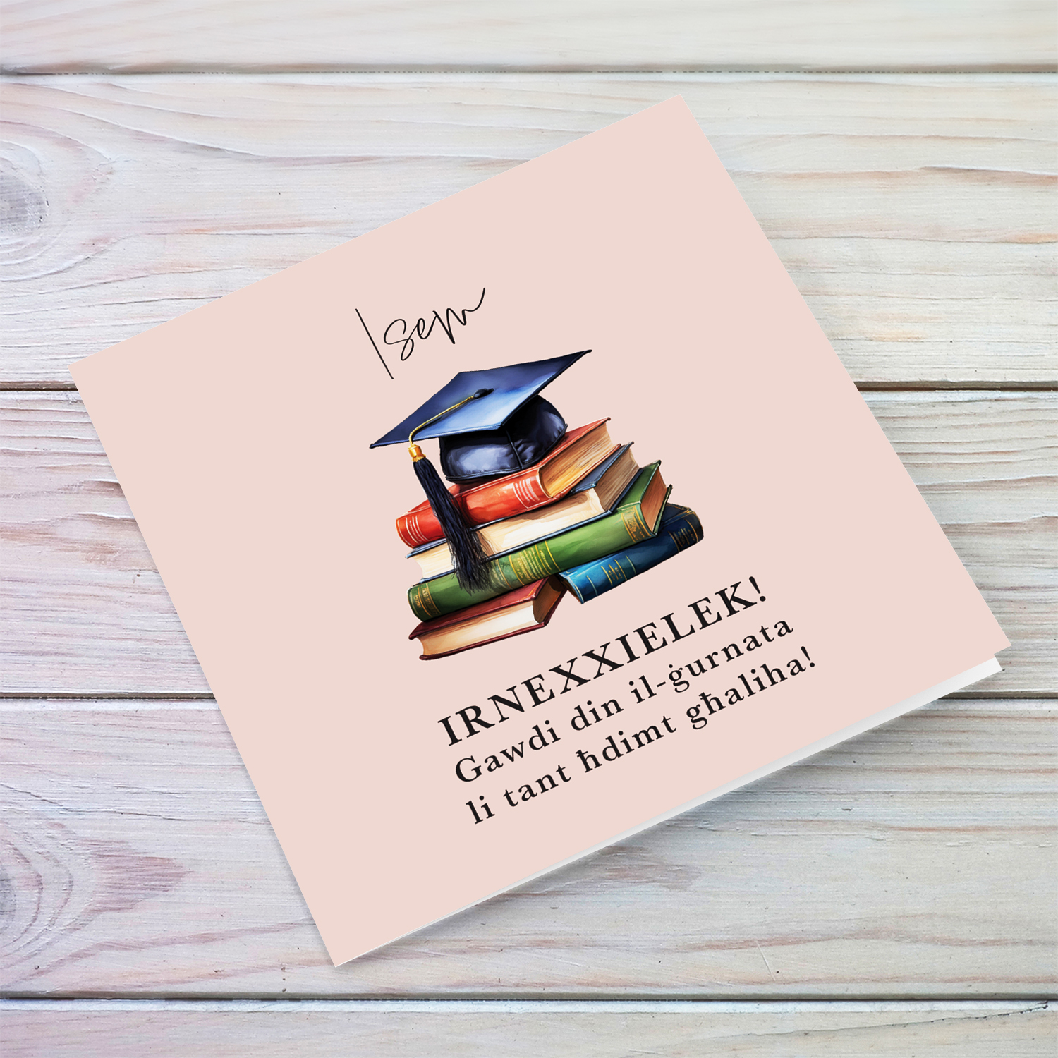 A graduation card featuring a graduation hat sitting on a stack of books, in light pink background in Maltese (Personalisable)