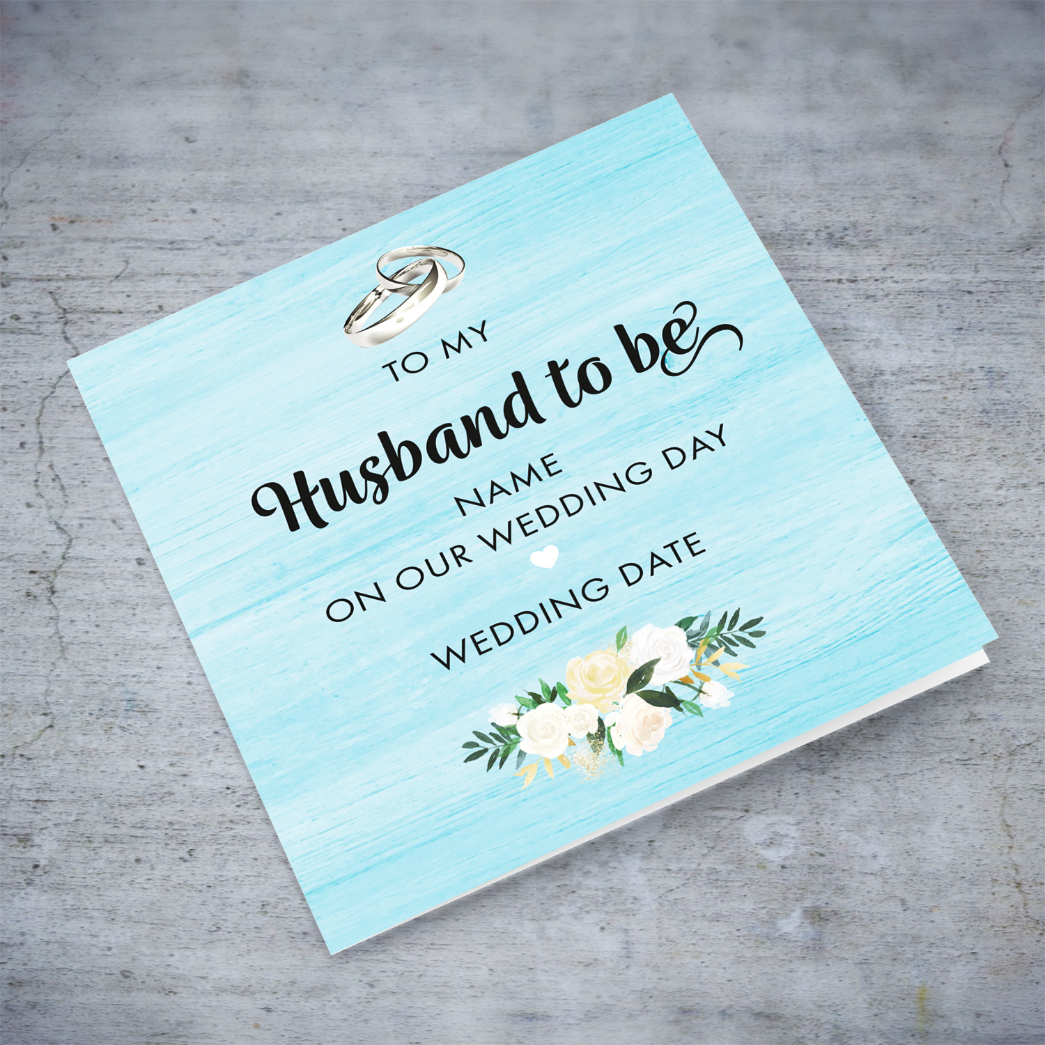 Husband-to-be wedding card with light blue background, wedding bands and white flowers in English
