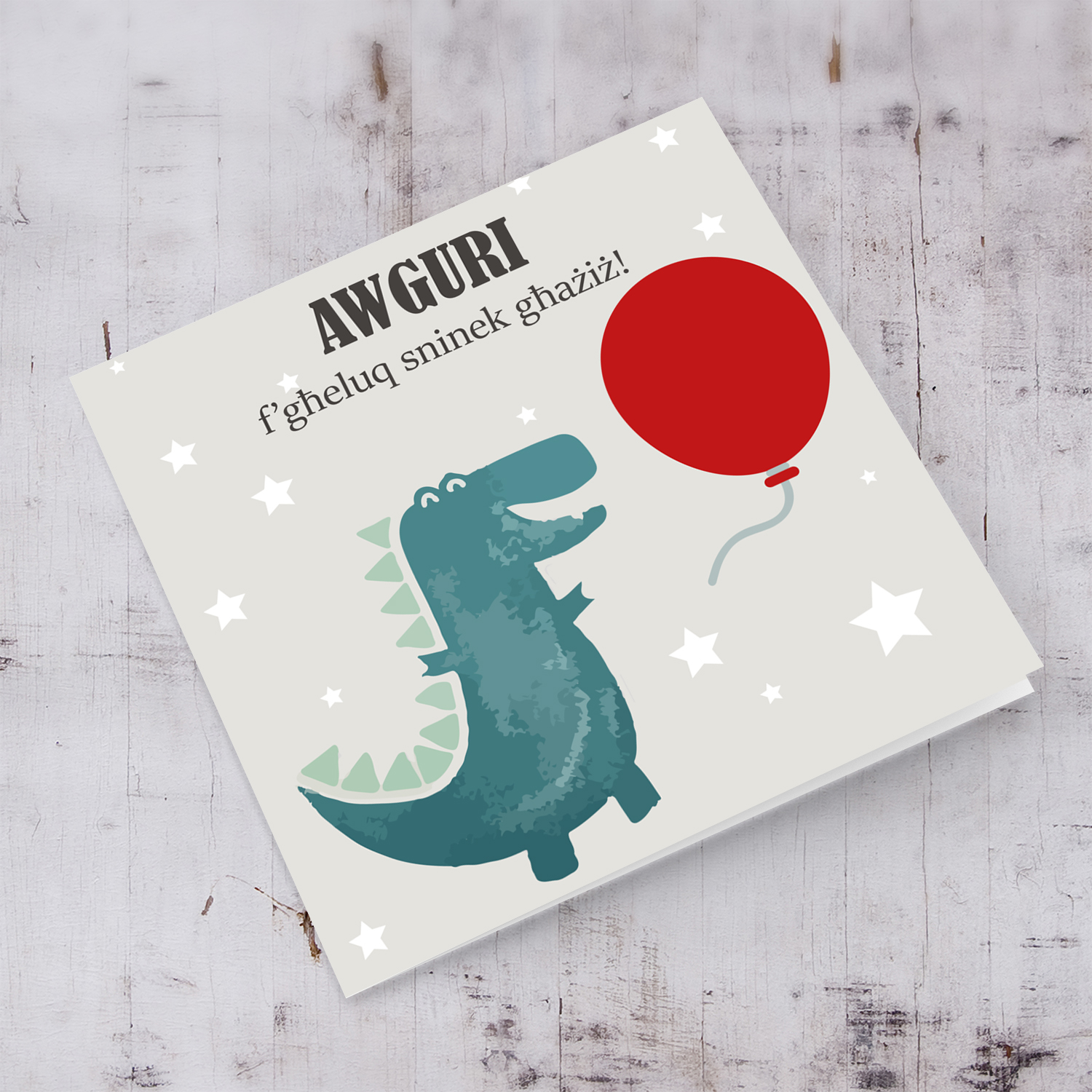 Dinosaur themed birthday card for boy holding red balloon in Maltese