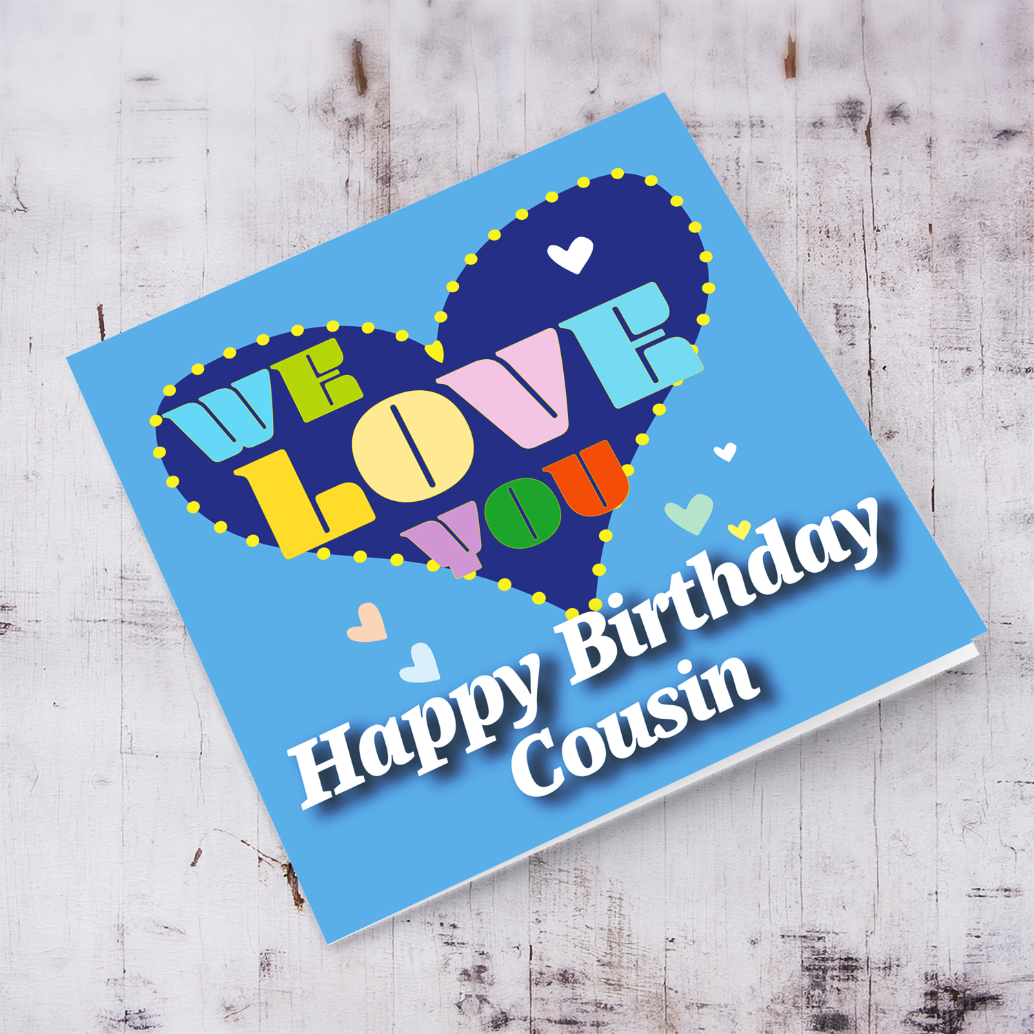 Blue background birthday card with big blue heart for Cousin, with a big WE LOVE YOU and scattered hearts in English