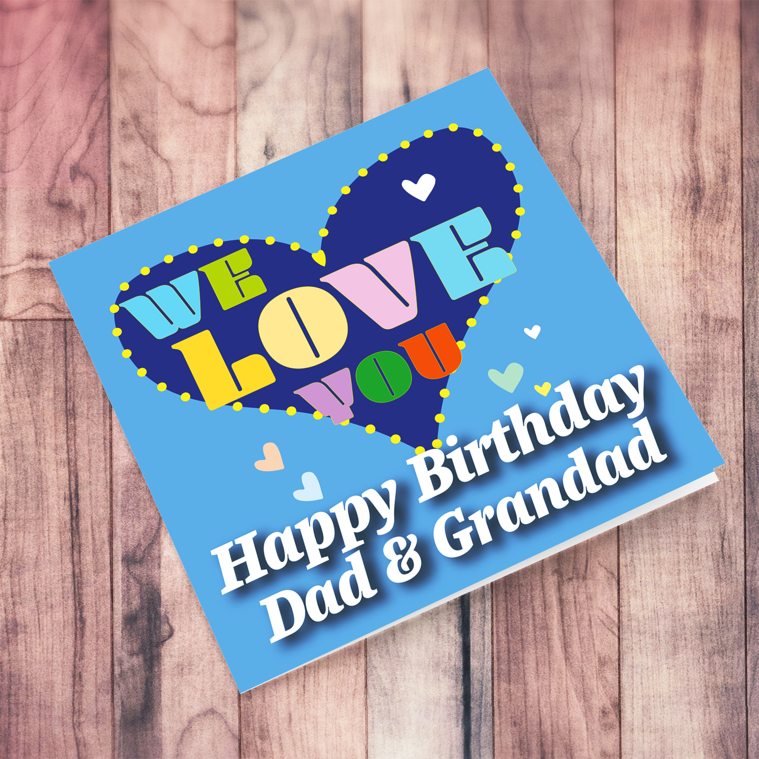 Blue background birthday card with big blue heart for dad & grandad, with a big WE LOVE YOU and scattered hearts in English