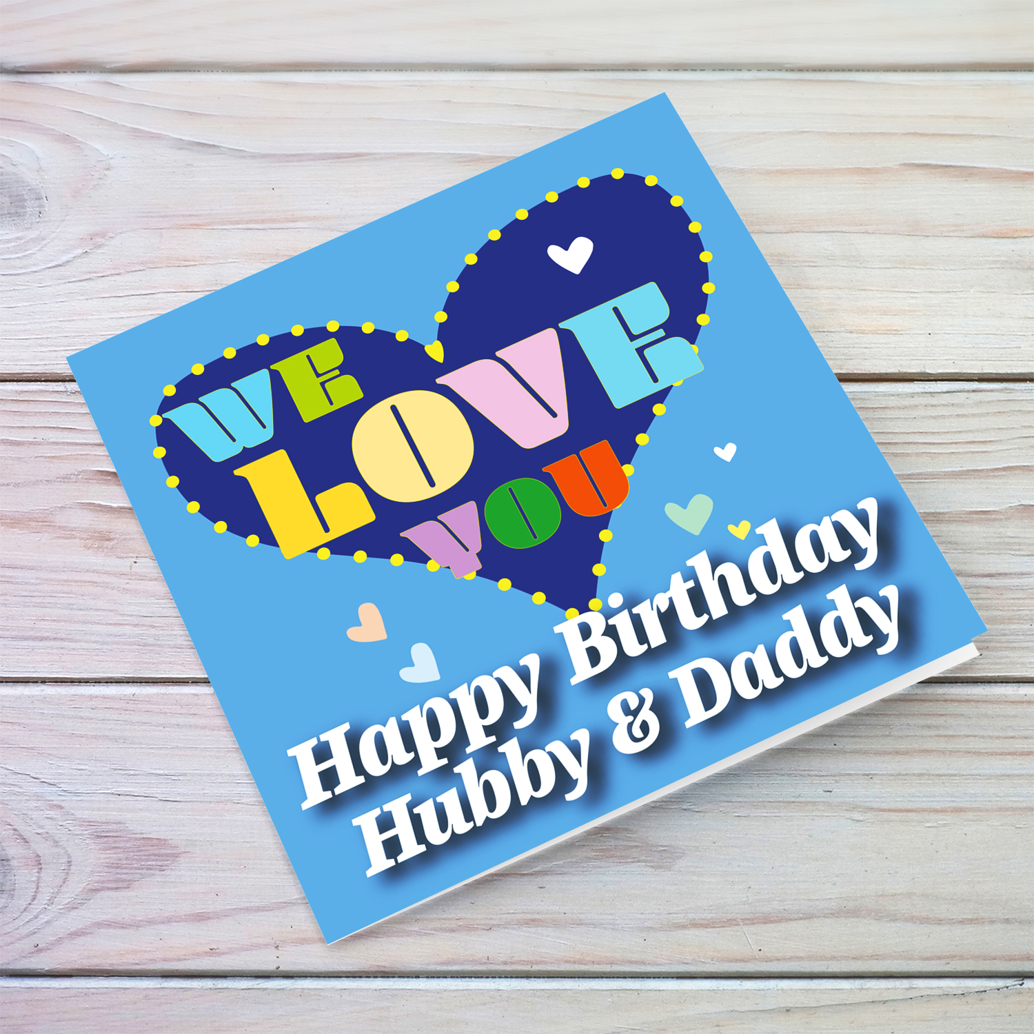 Blue background birthday card with big blue heart for husband & daddy, with a big WE LOVE YOU and scattered hearts in English