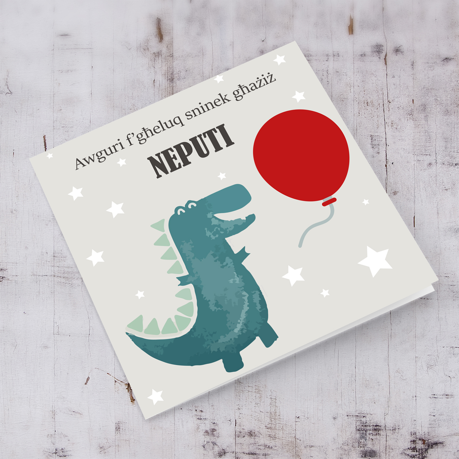 Dinosaur themed birthday card for nephew holding red balloon in Maltese