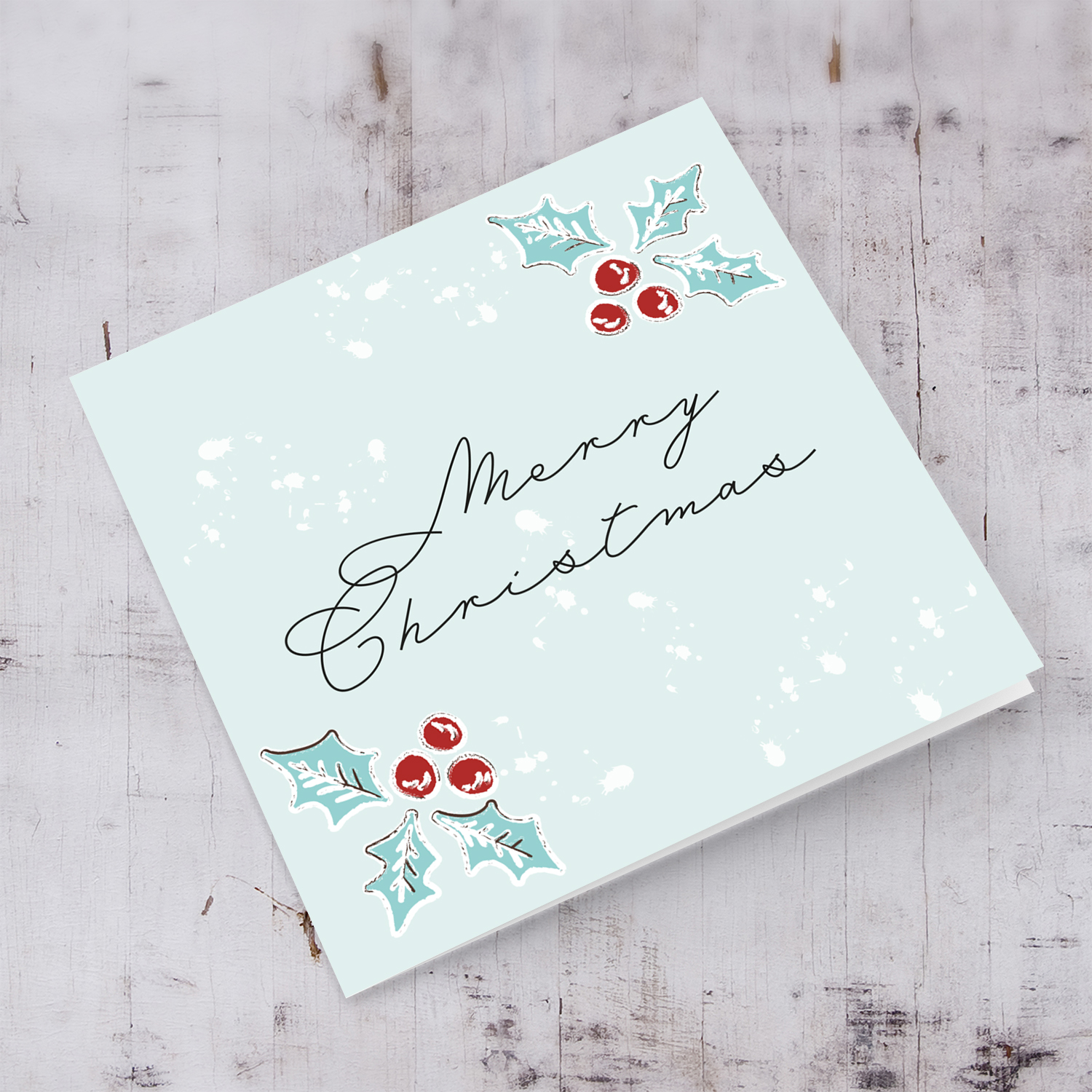 Christmas holly, scattered snow, and light background open Christmas card in English