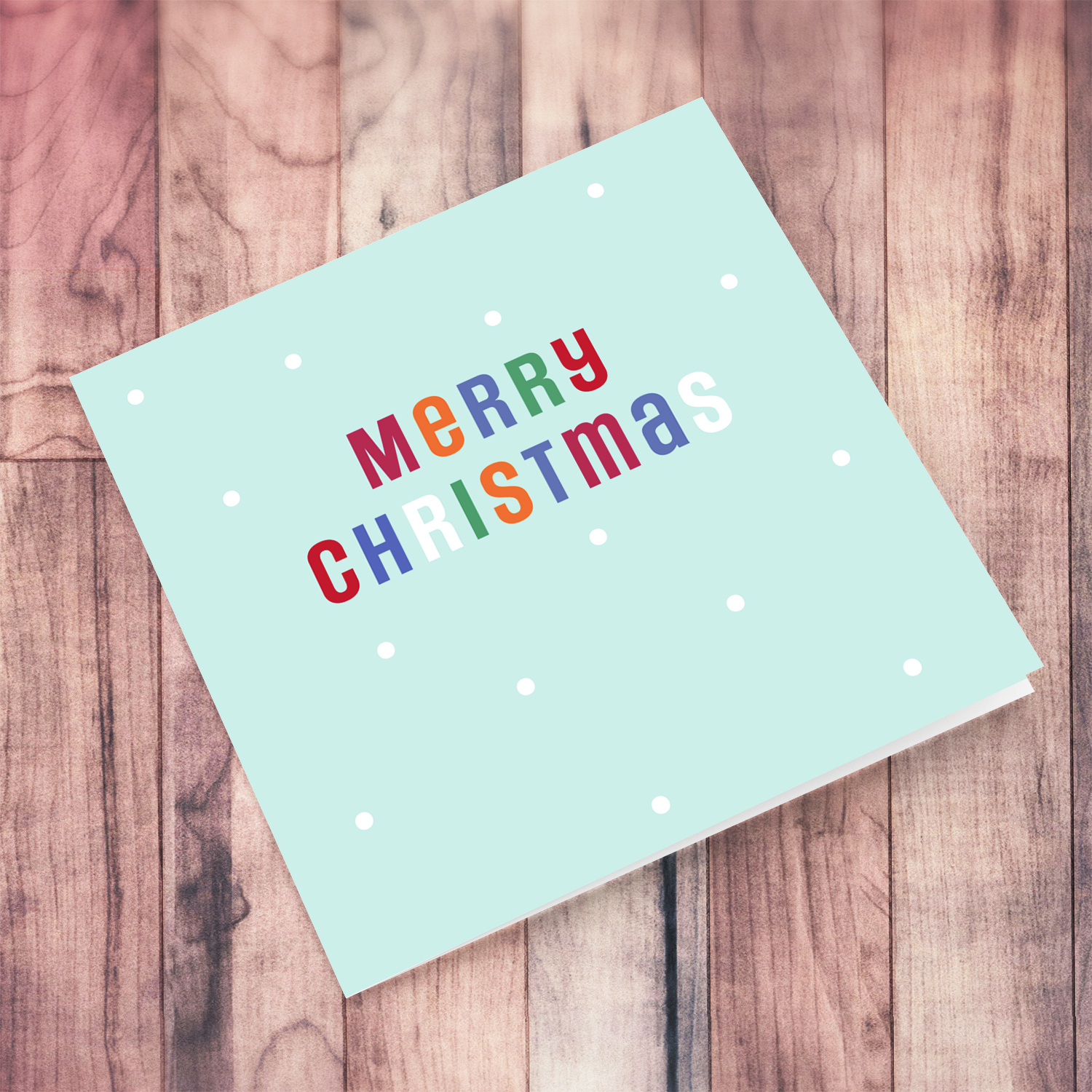 An open Christmas card in a light pastel blue/green background with colourful text in English
