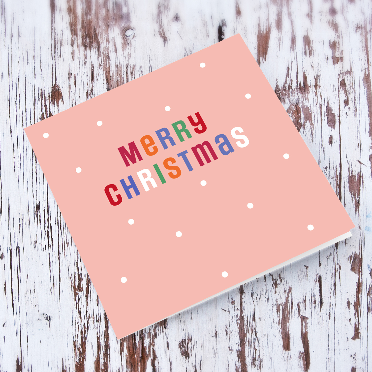 An open Christmas card in a light pink background with colourful text in English