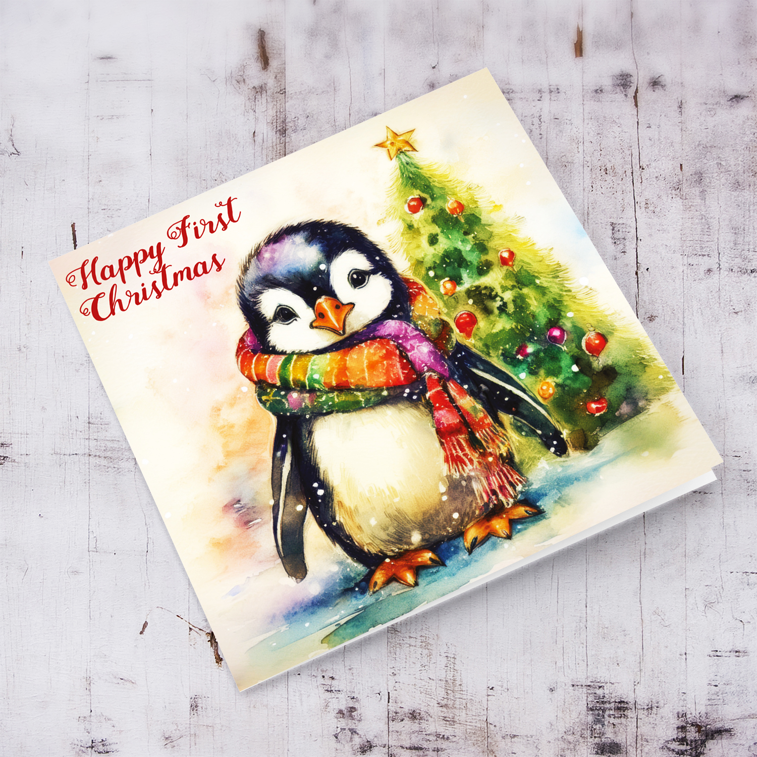 Happy First Christmas card - featuring a cute penguin wearing a colourful scarf in English