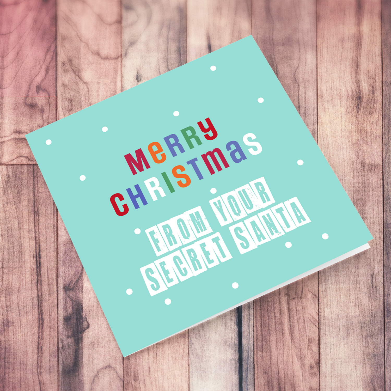 An cute Christmas card in a light blue background with colourful text - from your secret santa in English