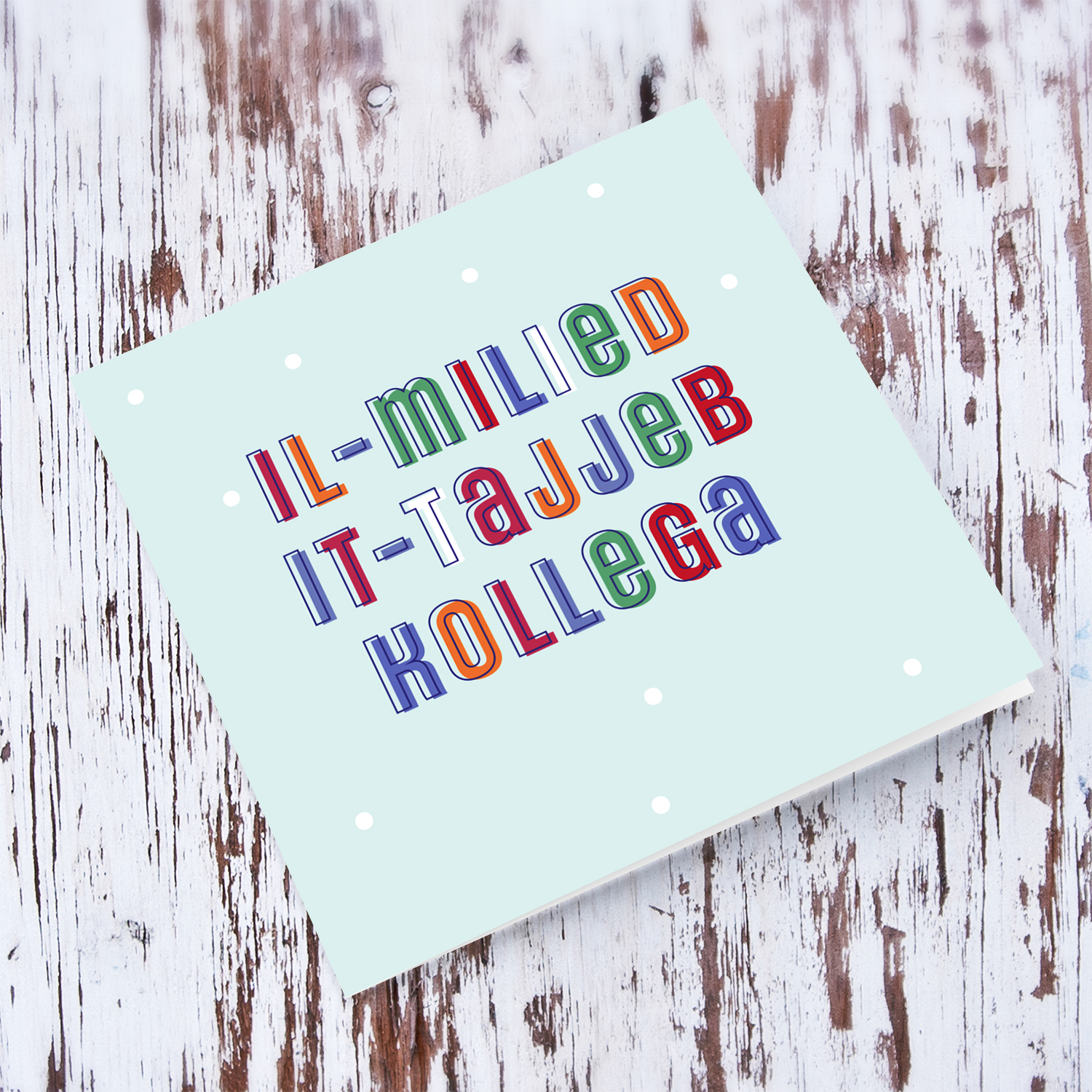 A cute Christmas card in a light blue background with colourful text for work colleague in Maltese