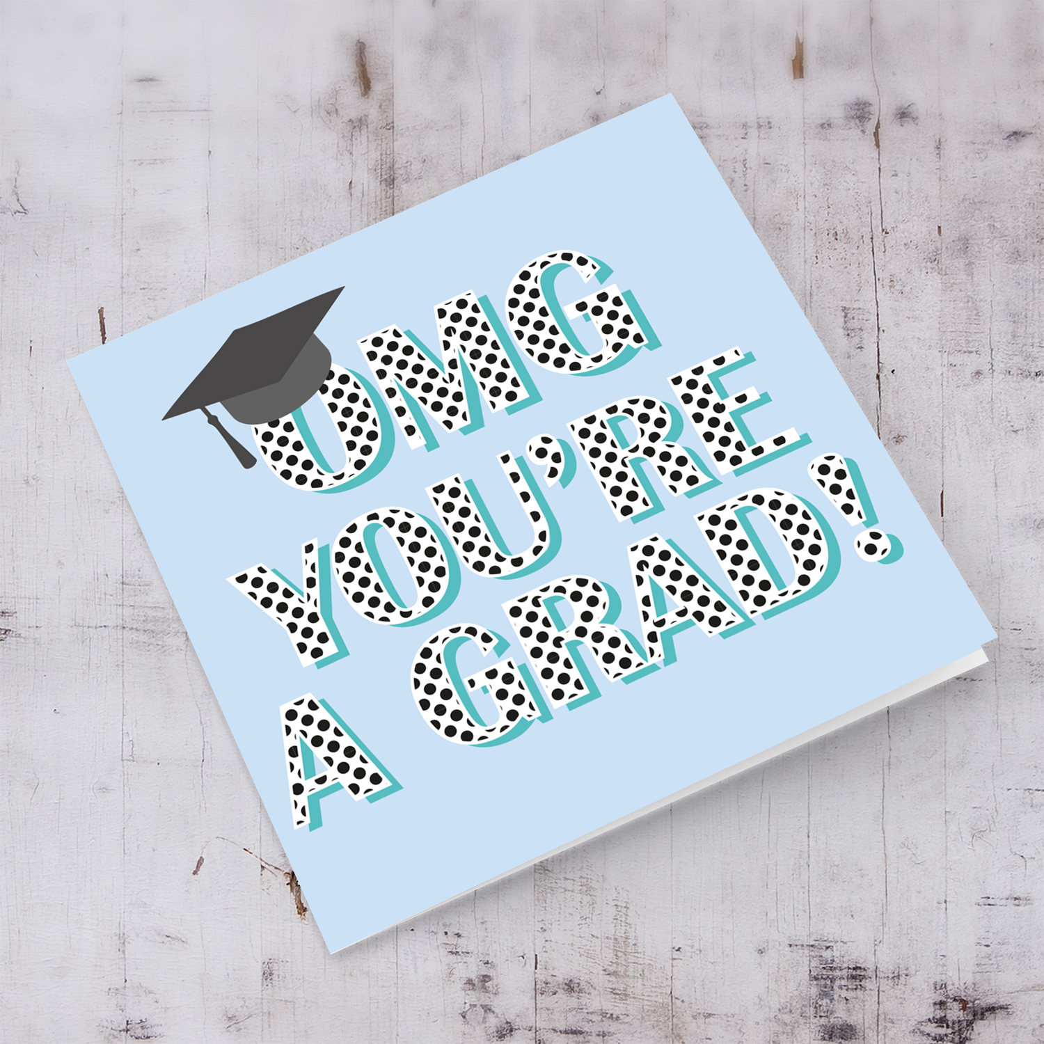 Light blue background graduation card with polka dot wording and graduation hat in English