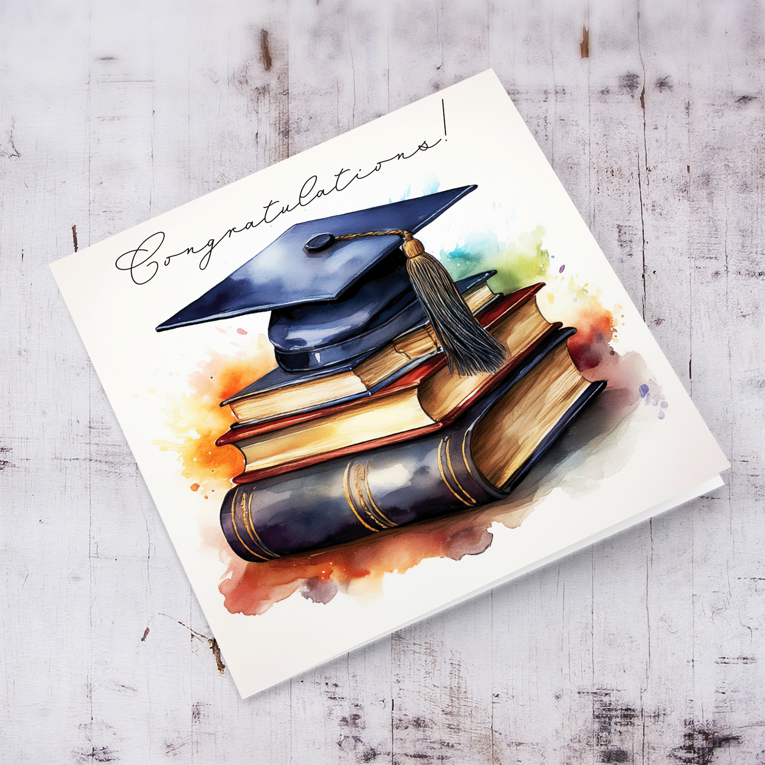 An open graduation card featuring a graduation hat sitting on a stack of books, in watercolours in English