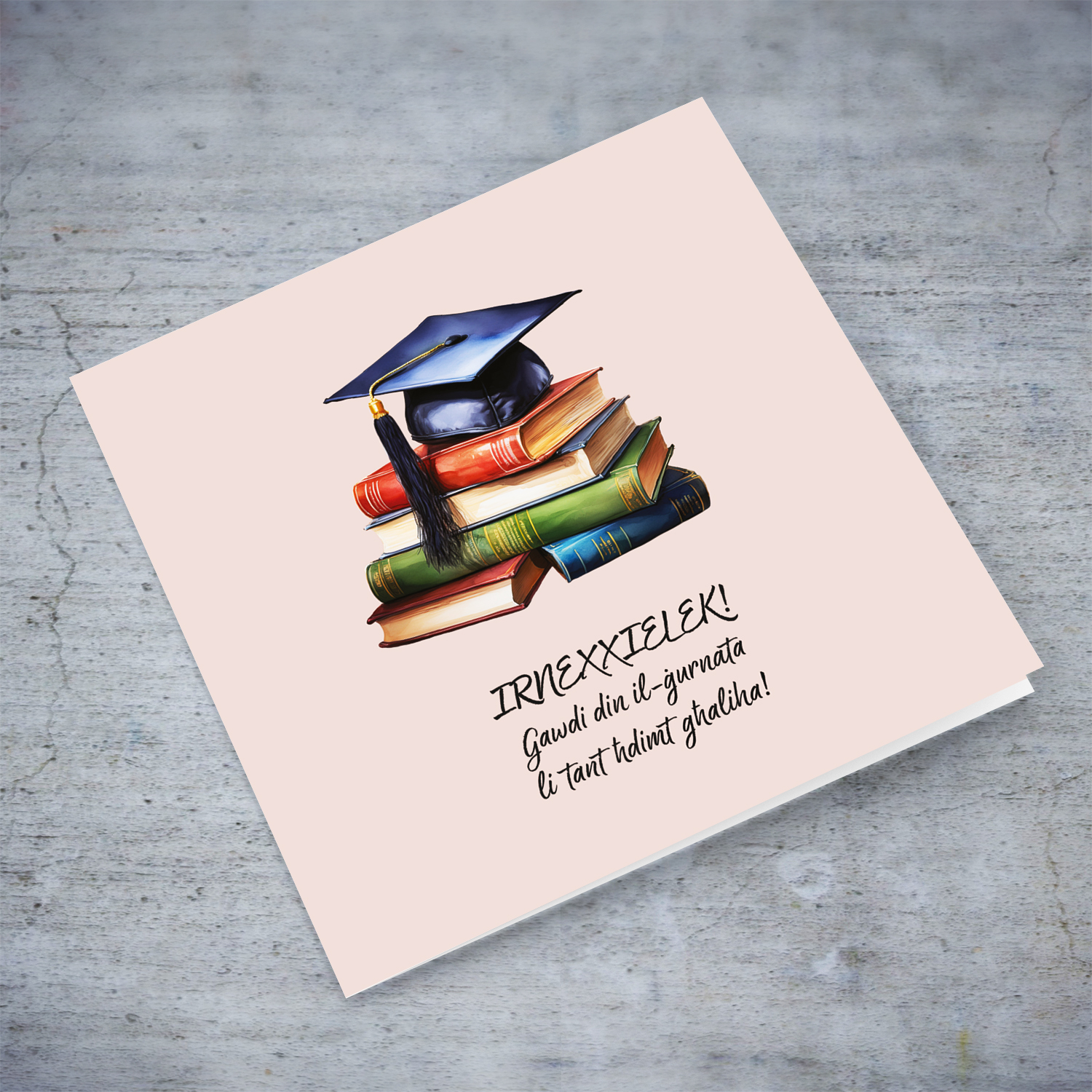 A graduation card featuring a graduation hat sitting on a stack of books, in pink background in Maltese