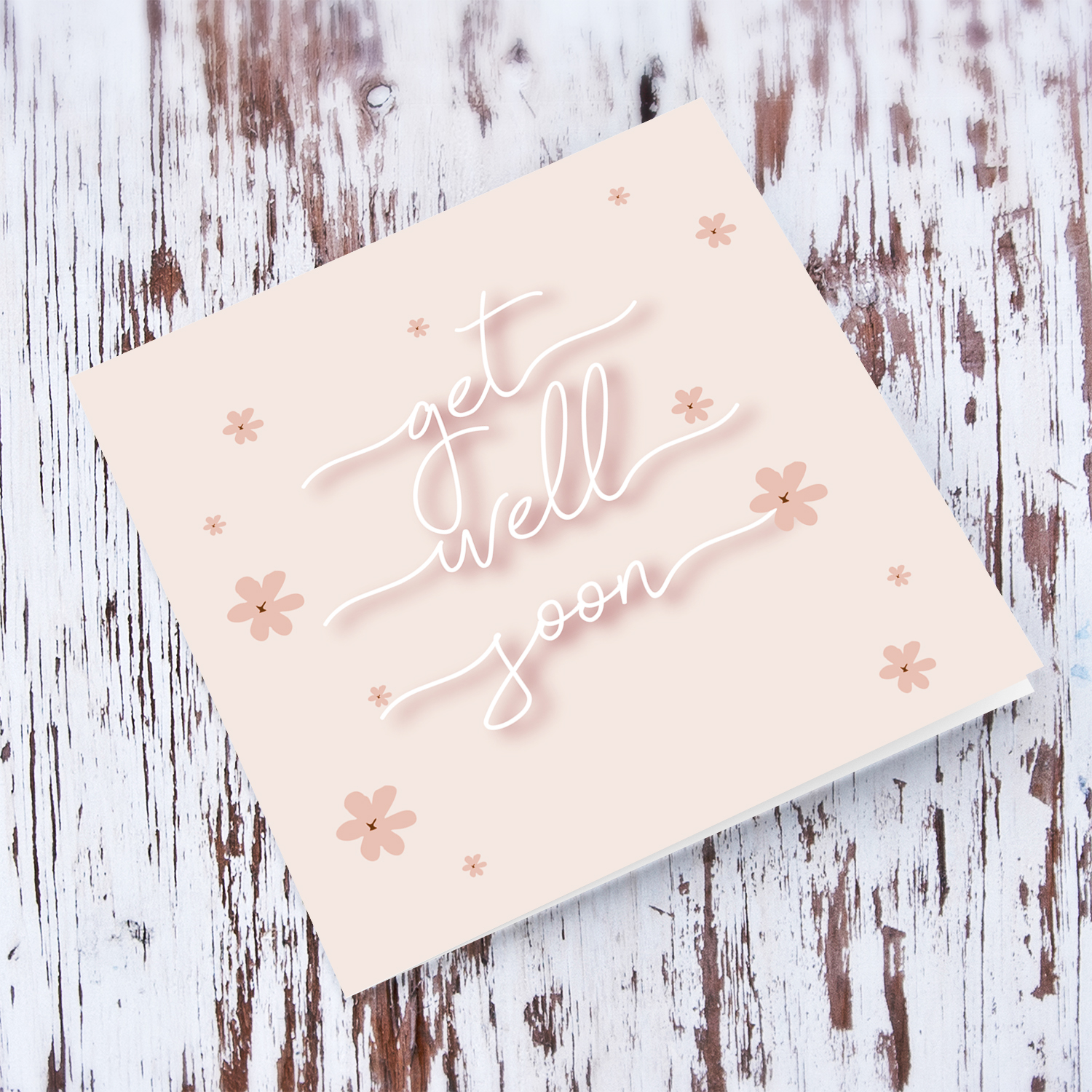 Light pink background get well soon card with scattered pink flowers and white text in English