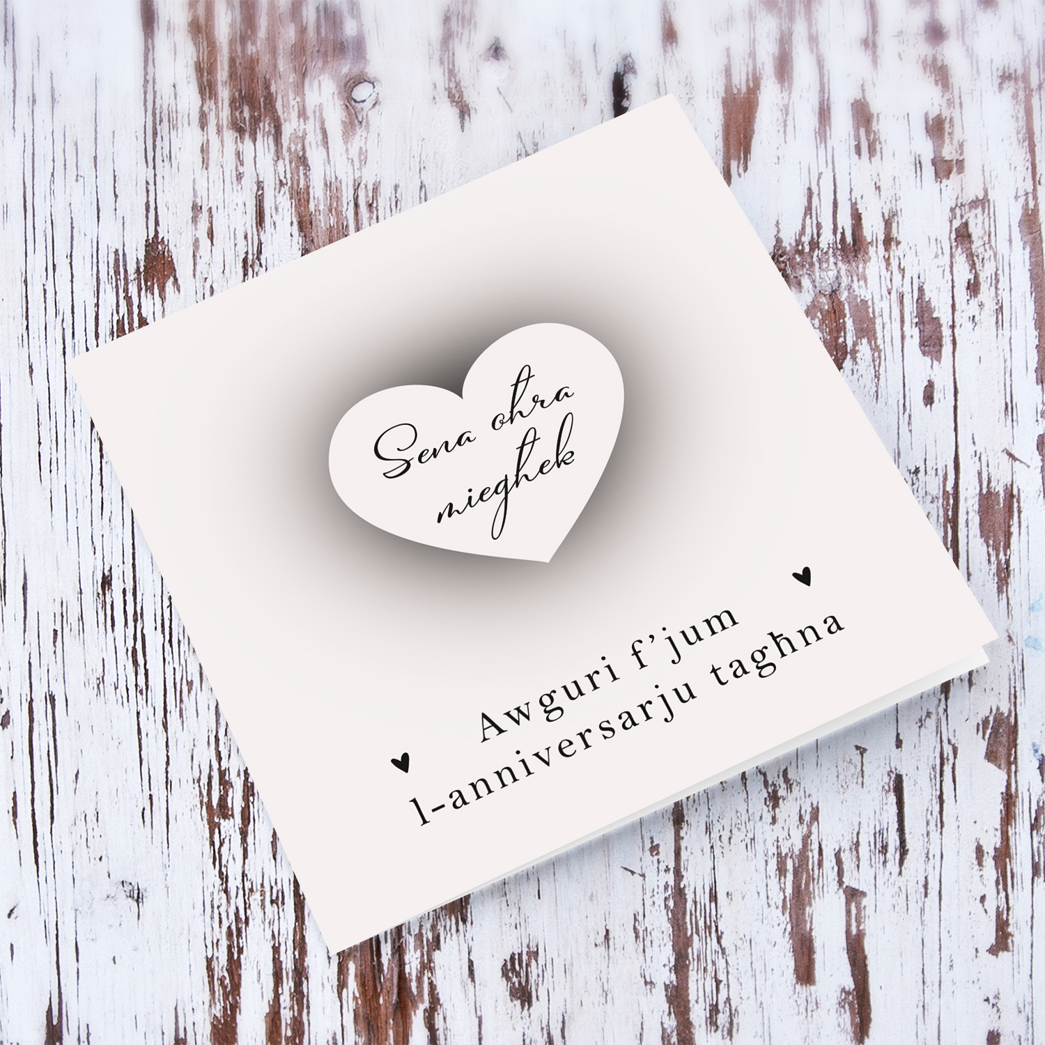 A neutral background minimalistic Anniversary card with a shadowed heart in the centre in Maltese